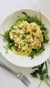 No-mayo egg salad served over a bed of arugula in a bowl with a spoon beside it.