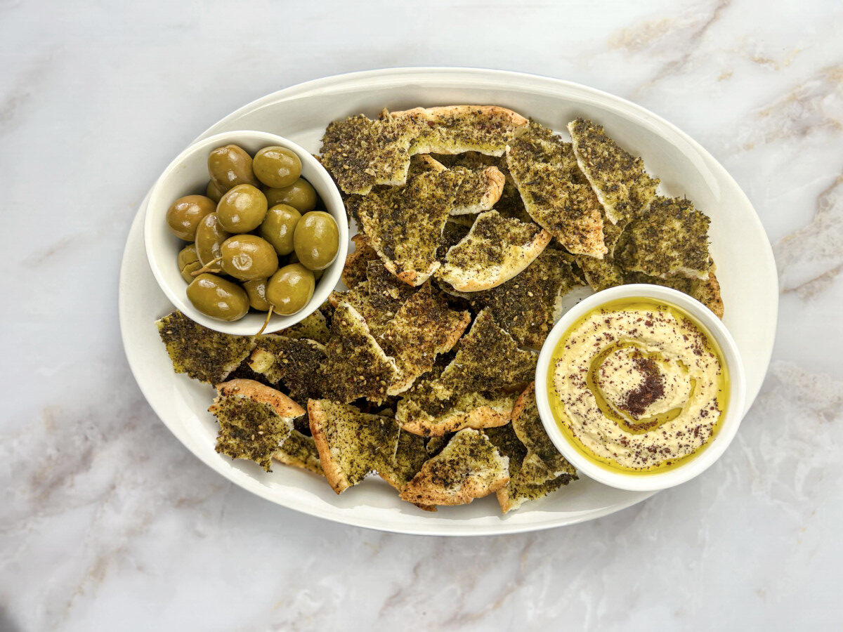 a platter of pita chips, hummus and olives