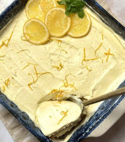 Meyer Lemon Tiramisu garnished with fresh Meyer lemon slices and mint, with a big spoon scooping out a creamy portion.