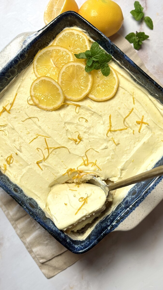 Meyer Lemon Tiramisu garnished with fresh Meyer lemon slices and mint, with a big spoon scooping out a creamy portion.