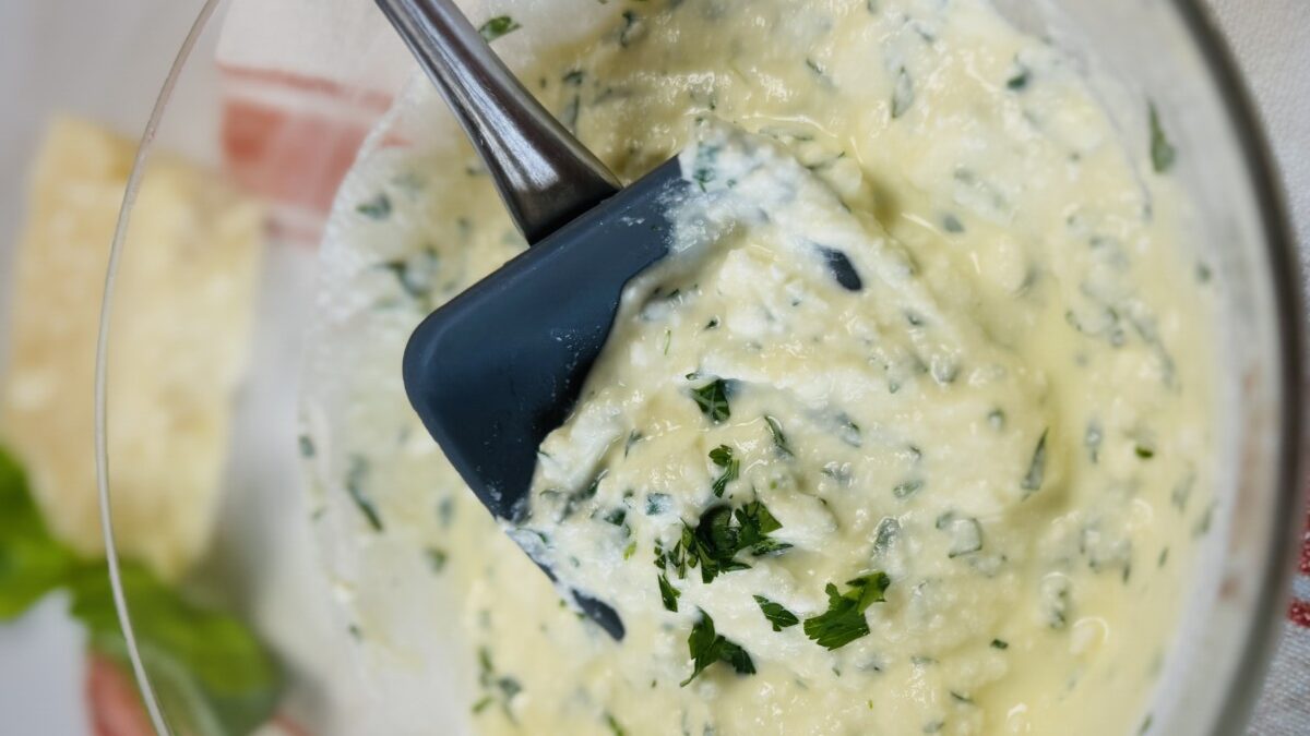 Ricotta, feta, and parsley being mixed in a bowl to create a creamy filling for stuffed pasta shells.