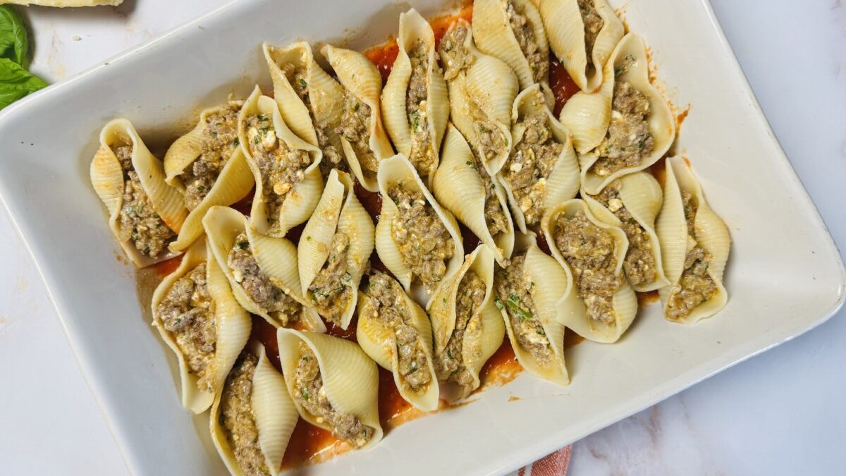 Stuffed pasta shells filled with spiced meat and cheese, neatly arranged in a large baking dish.