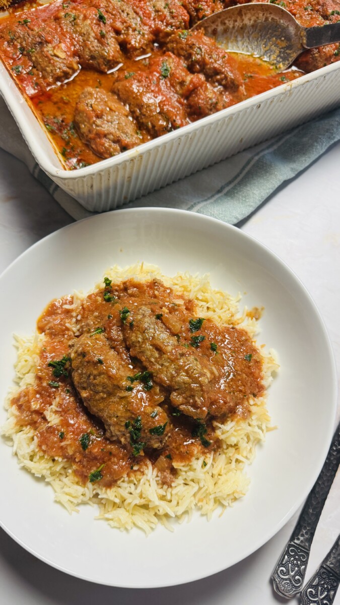 Greek meatballs in tomato sauce served over a bed of fluffy white rice, garnished with fresh parsley.