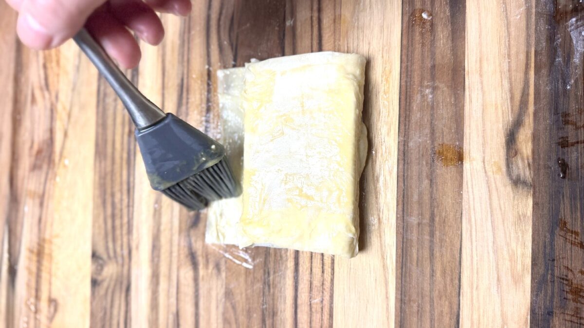 Feta cheese fully wrapped in phyllo dough with edges sealed, ready for baking.