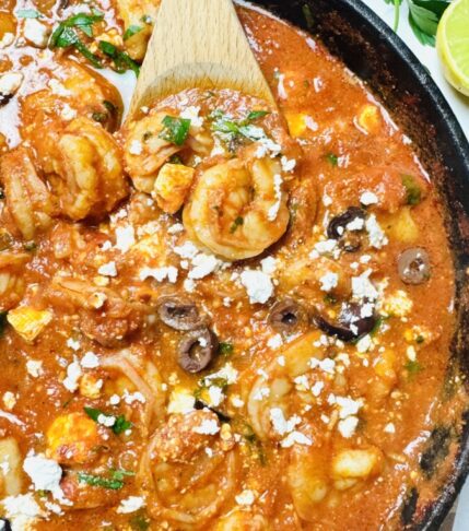 Shrimp being mixed and coated in a rich tomato sauce, ensuring every piece is full of flavor.