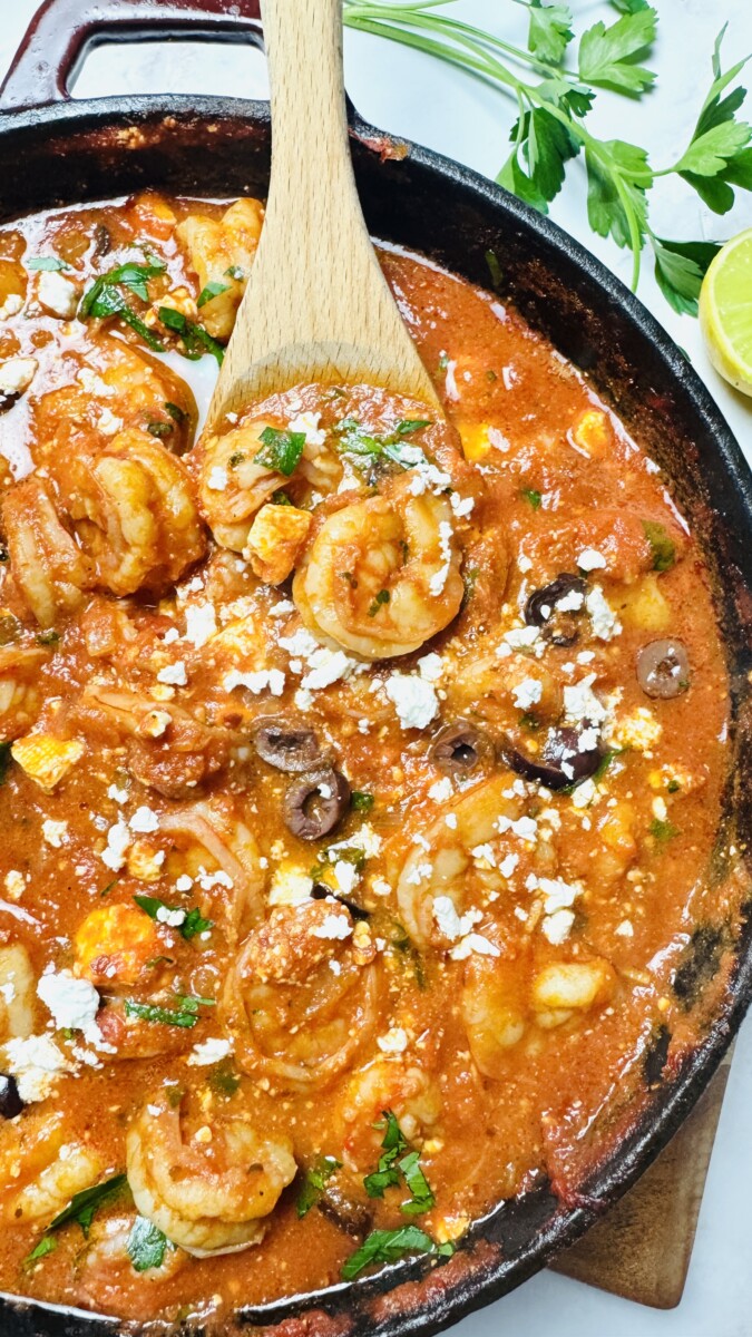 Shrimp being mixed and coated in a rich tomato sauce, ensuring every piece is full of flavor.