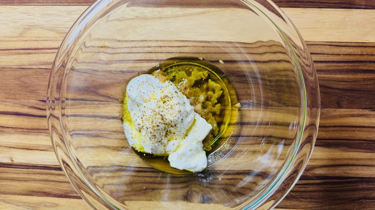 Ingredients for creamy yogurt dressing, including Greek yogurt, preserved lemon, olive oil, and lemon juice, in a bowl ready to be mixed.