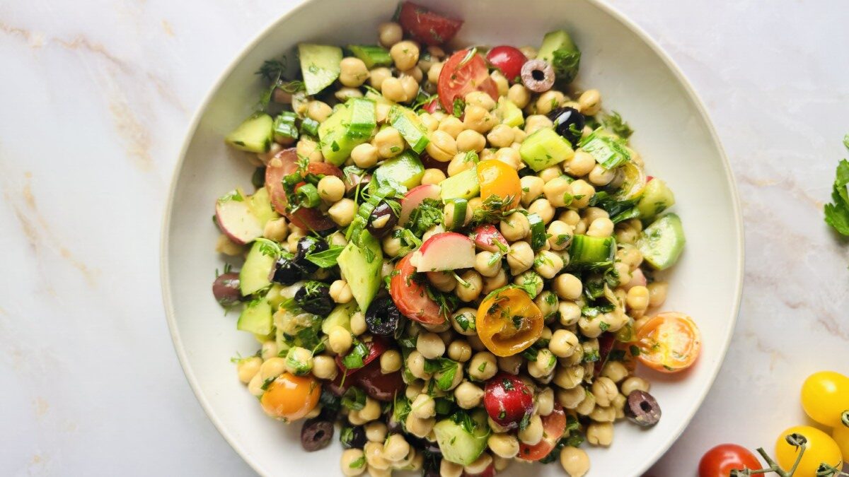 Mediterranean Garbanzo Bean Salad tossed with pomegranate molasses dressing in a large bowl.