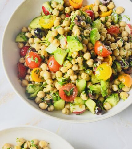 Mediterranean Garbanzo Bean Salad tossed with pomegranate molasses dressing in a large bowl."