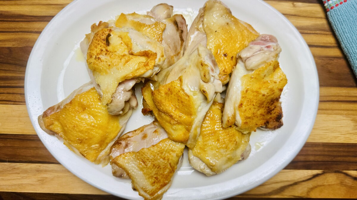 Golden-browned chicken thighs resting on a platter after searing, ready to be braised for Pomegranate Roasted Chicken.