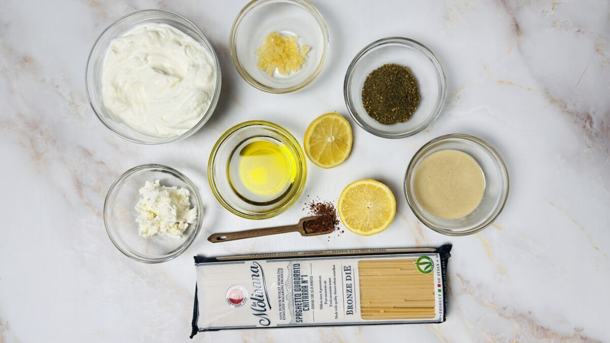 Ingredients for creamy za’atar pasta arranged on a countertop, including pasta, yogurt, garlic, za’atar, olive oil, and lemon.