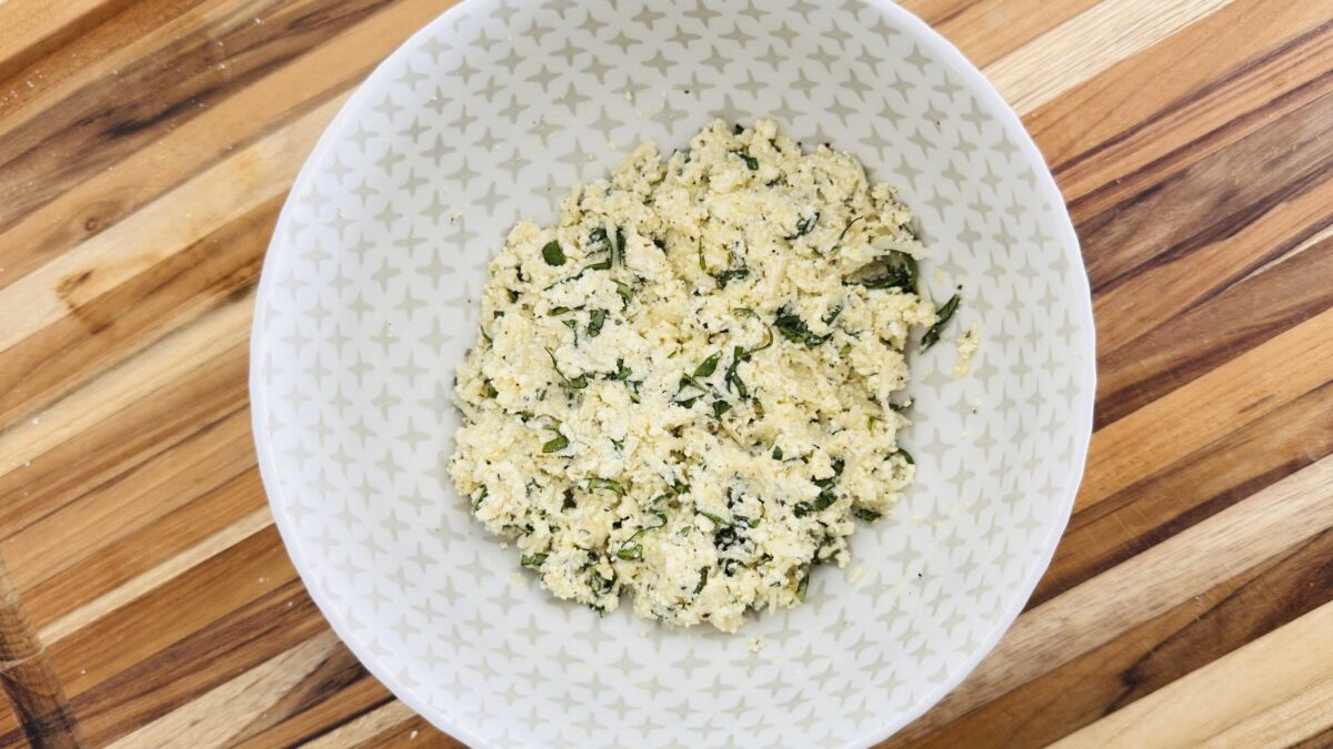 Bowl of creamy ricotta filling mixed with egg, parmesan, garlic, and fresh basil for Eggplant Rollatini.