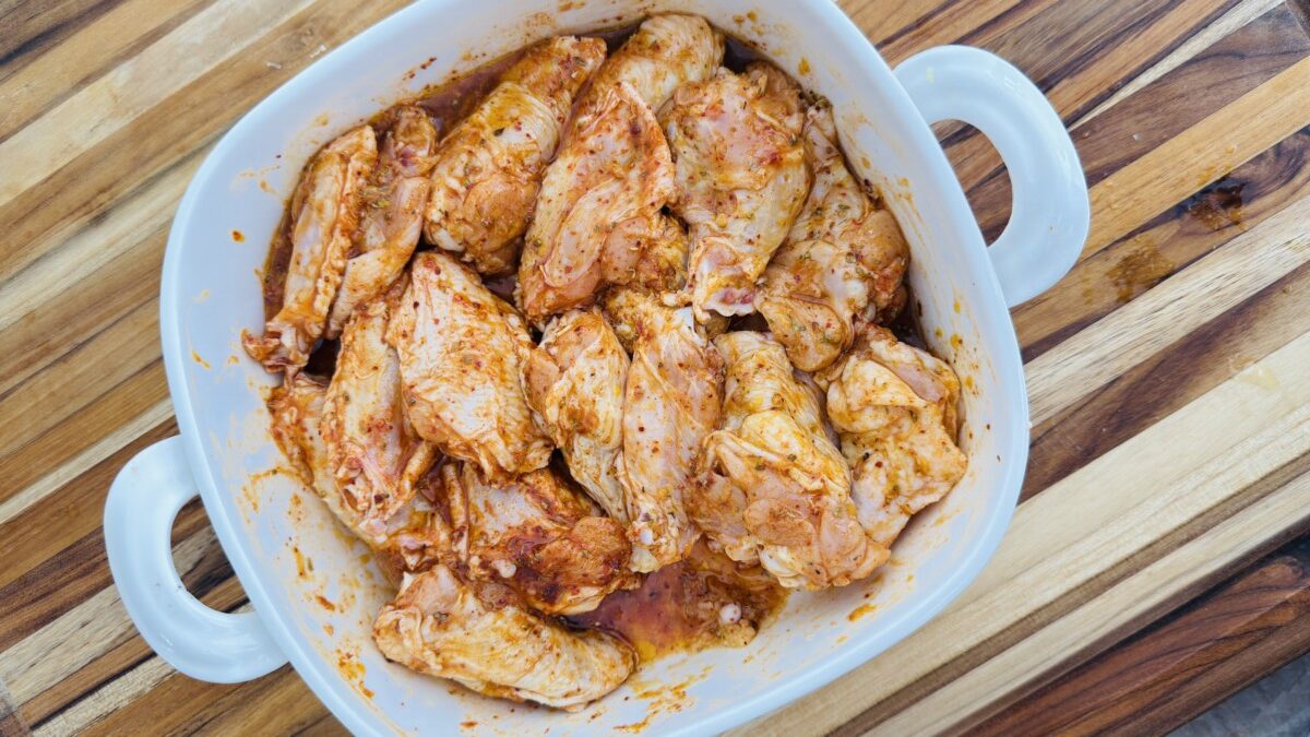 Chicken wings fully coated in a lemon-garlic marinade with visible herbs and spices.