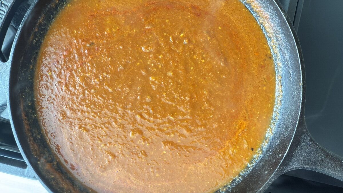 Tomato sauce simmering in a skillet with onions, garlic, jalapeño, and spices.