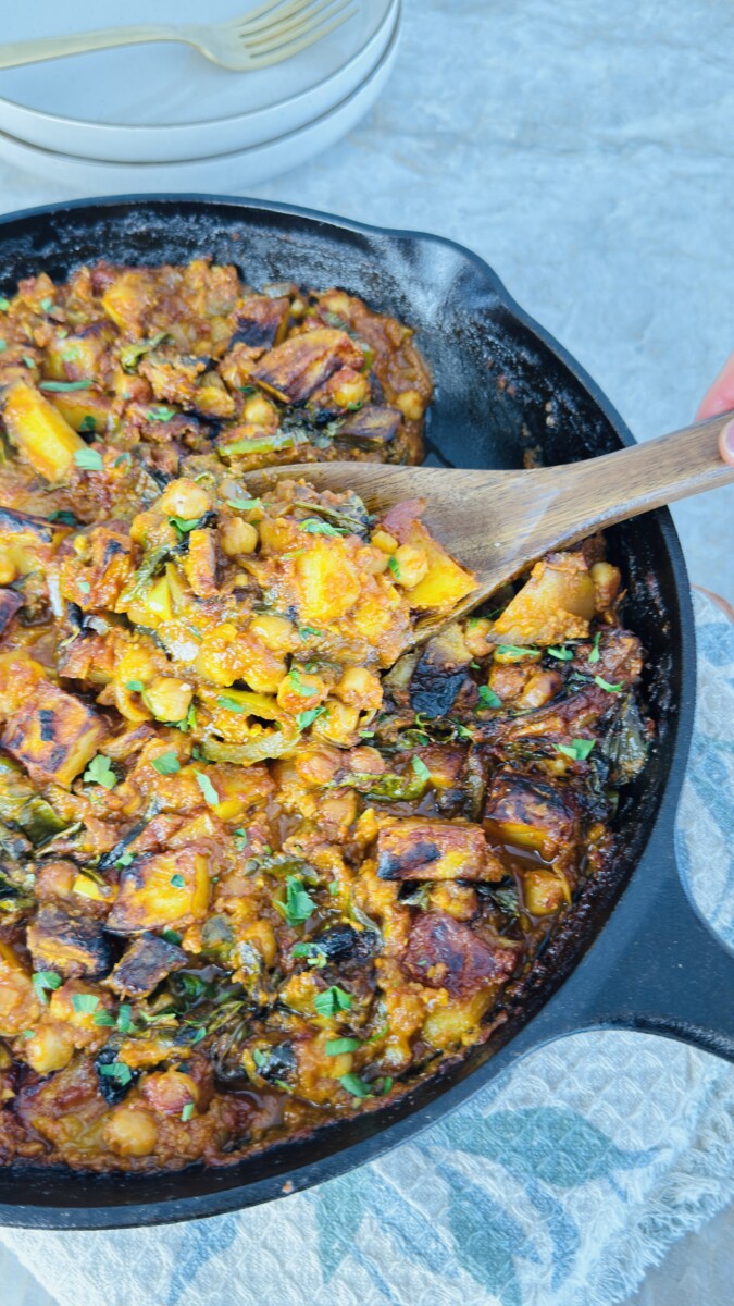 Baked Mediterranean eggplant stew with chickpeas, spinach, and golden vegetables, garnished with fresh parsley.