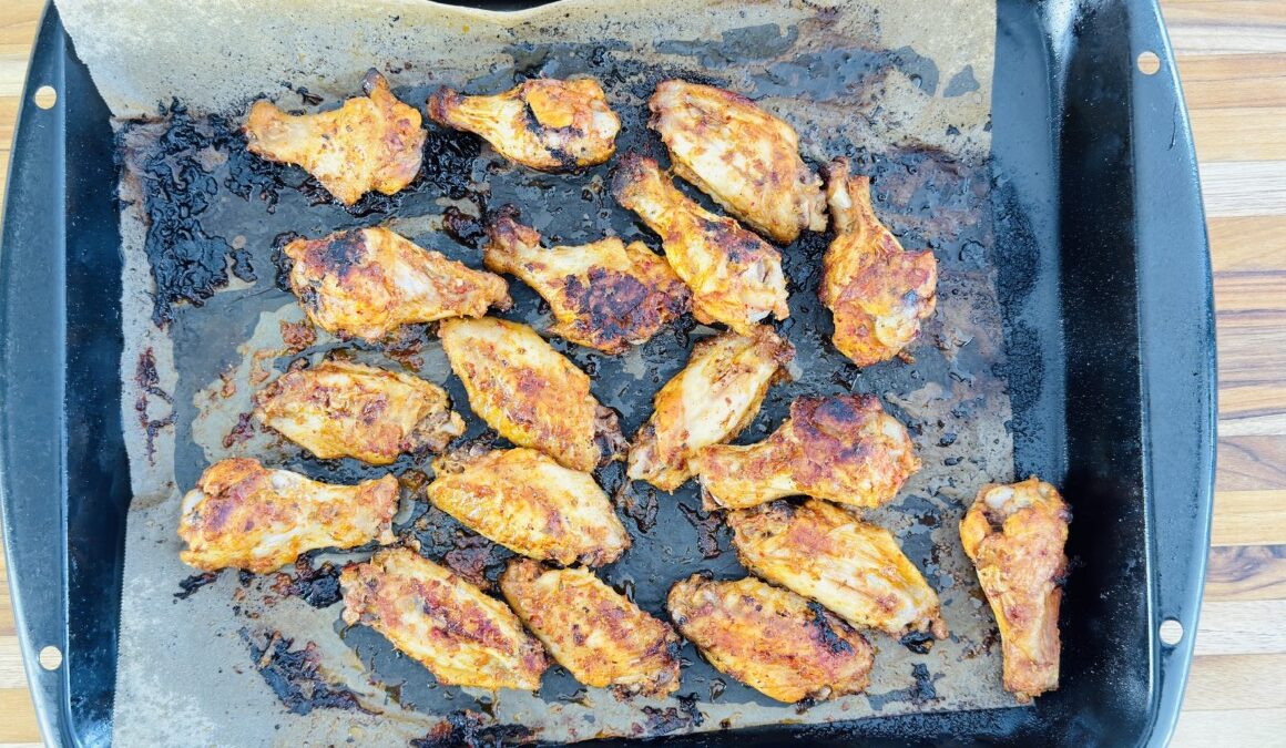 Golden baked chicken wings fresh out of the oven, arranged on a parchment-lined tray.