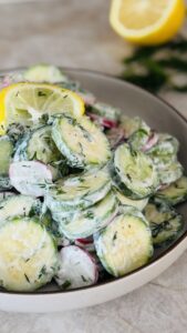 Creamy cucumber zucchini salad served on a platter, garnished with fresh herbs.