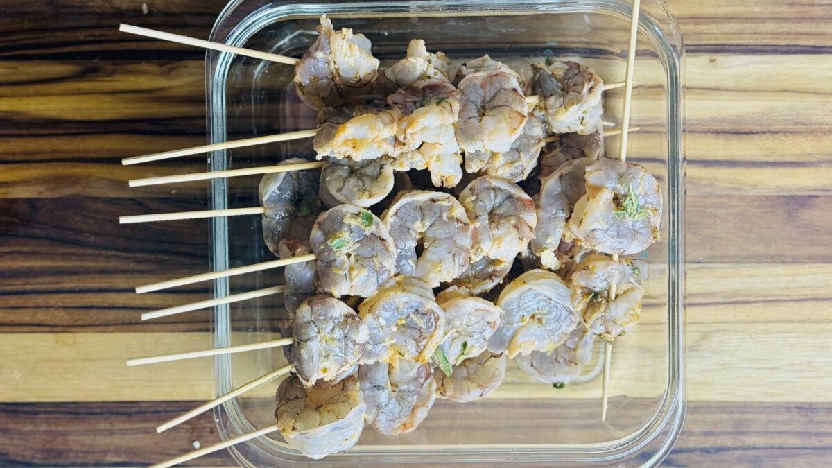 Marinated shrimp threaded onto wooden skewers, ready for grilling.
