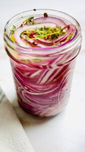 A single jar of vibrant pink pickled red onions, fully cooled and ready to use.