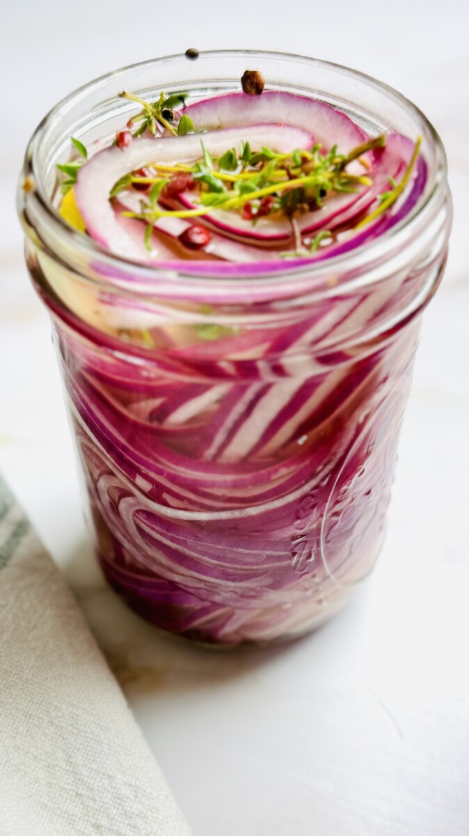 A single jar of vibrant pink pickled red onions, fully cooled and ready to use.
