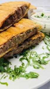 Golden grilled Arayes served on a plate with a creamy yogurt dip and garnished with herbs.