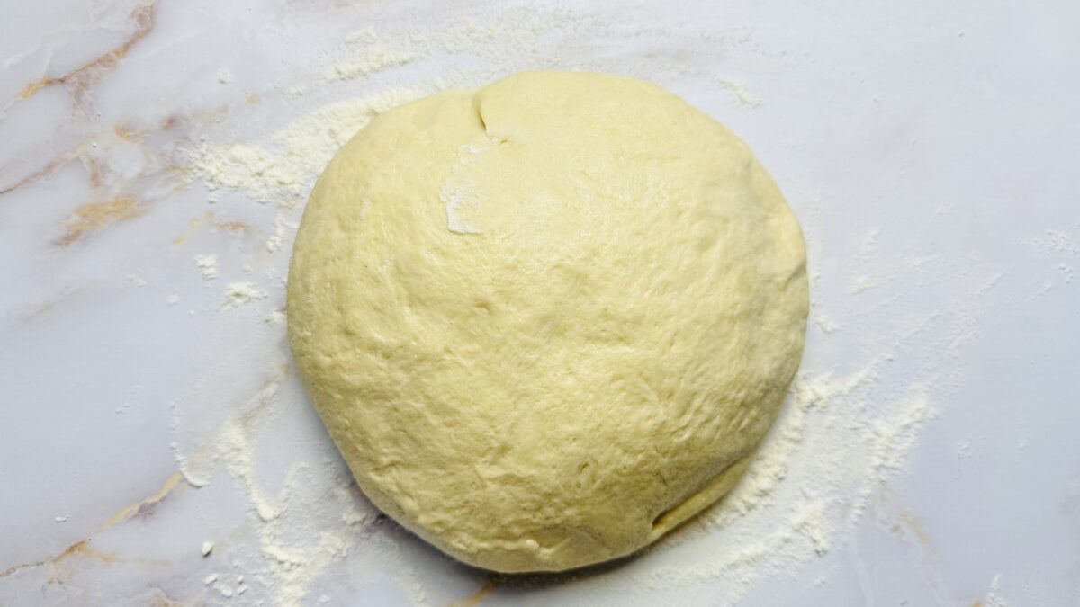 Fluffy risen dough transferred to a floured surface, ready to be divided and shaped.