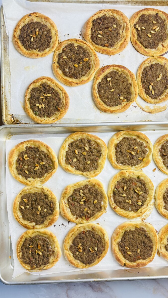 Golden brown sfeeha fresh out of the oven on a baking tray, with bubbling meat topping and lightly crisped edges.