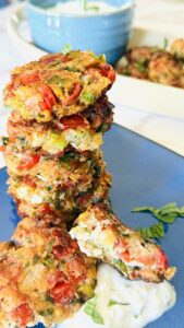 A tall stack of crispy tomato fritters piled on top of each other, showing their golden texture