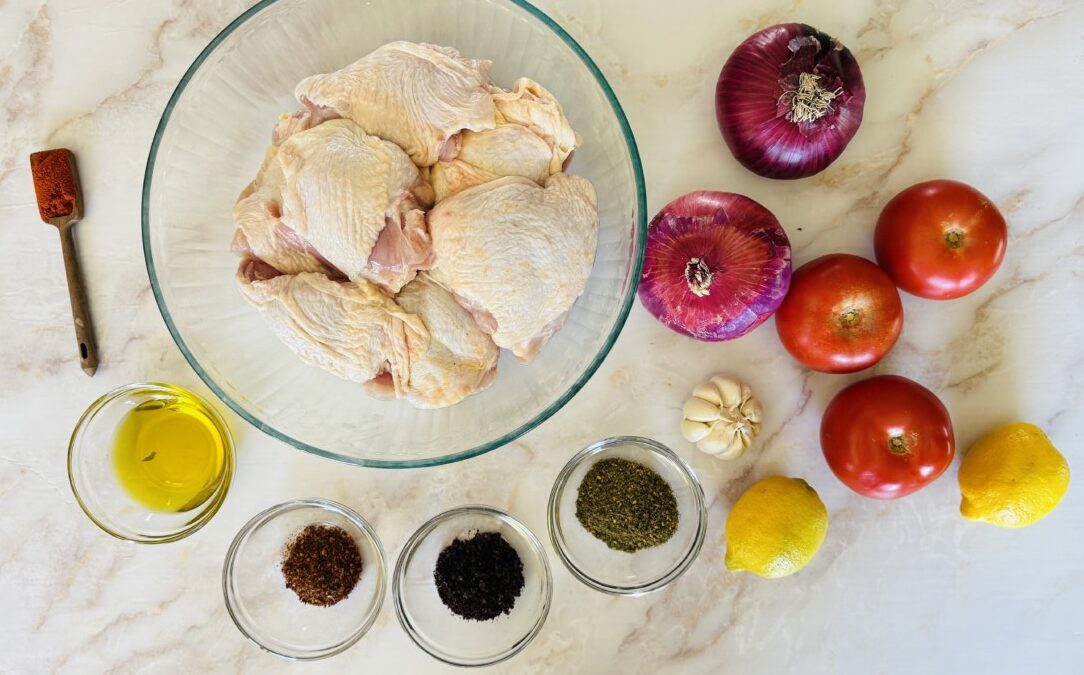 Ingredients for grilled chicken thighs including za’atar, sumac, garlic, lemon, olive oil, spices, and bone-in chicken thighs arranged on a surface.
