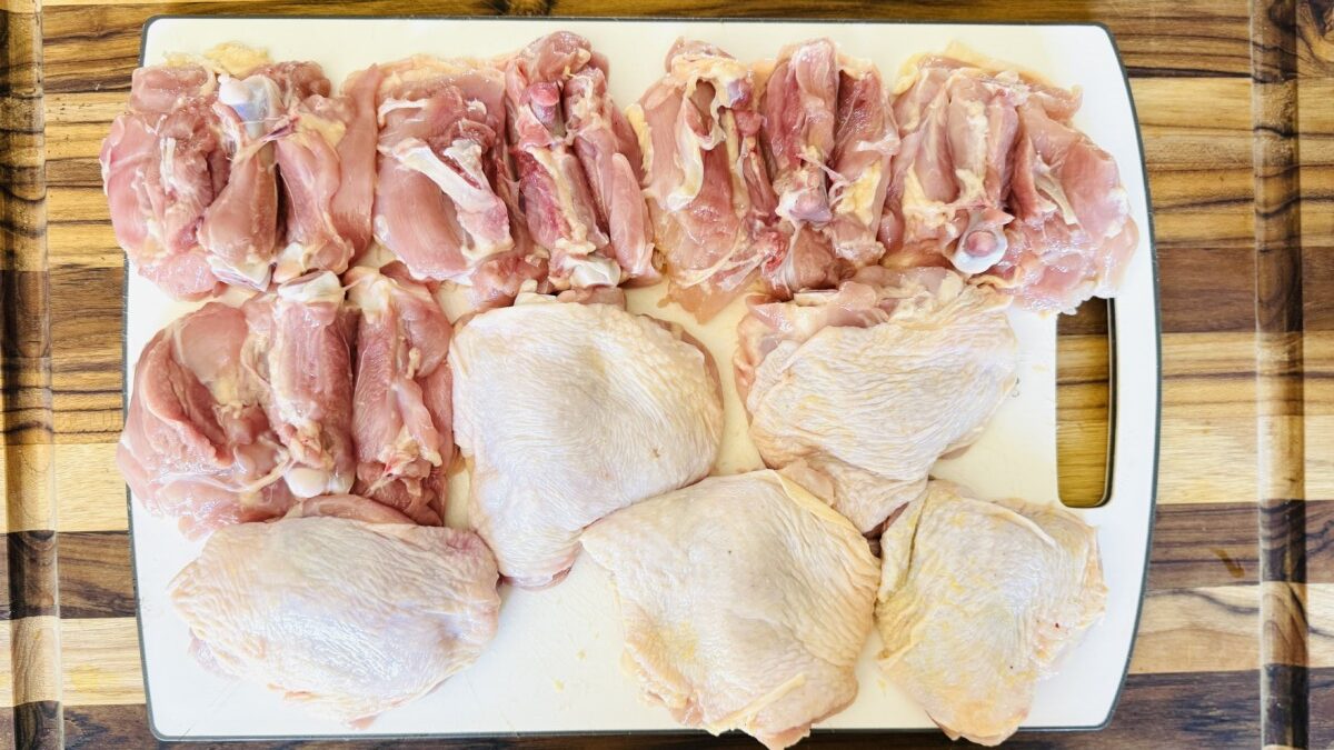 Bone-in chicken thighs cleaned, trimmed, and slit along the bone, ready for marinade.
