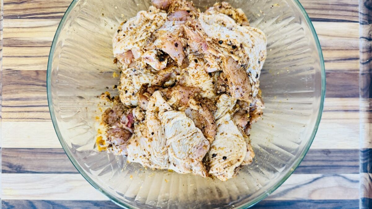 Chicken thighs fully coated in za’atar marinade resting in a bowl, ready to marinate for at least 2 hours.