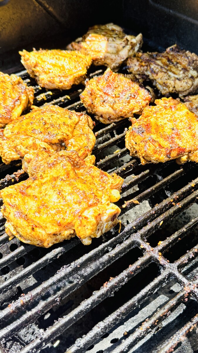 Chicken thighs on the cooler side of the grill cooking skin-side up over indirect heat.