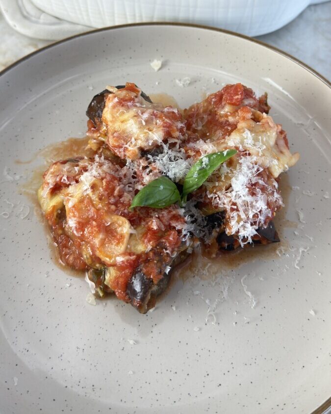 This Italian-inspired dish rolls thin eggplant slices around creamy ricotta, topped with marinara for a Mediterranean comfort-food favorite.