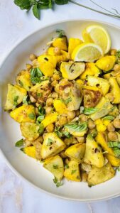 Finished sautéed summer squash with chickpeas, garnished with fresh herbs and a drizzle of olive oil, served warm.