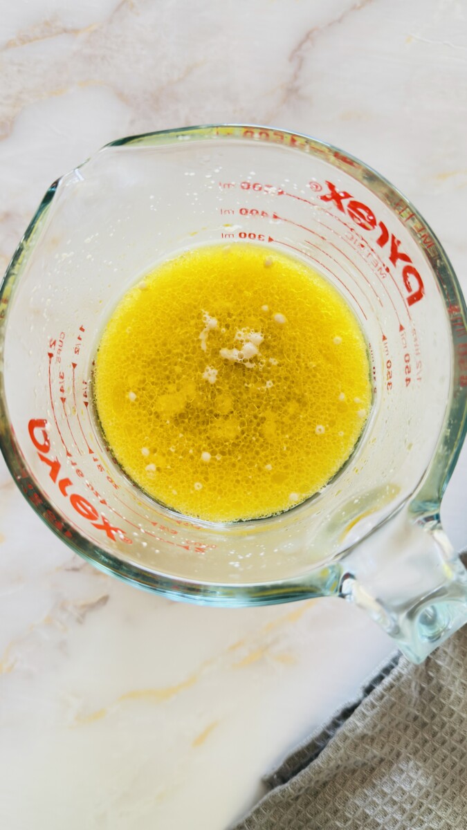 Mixing warm water and olive oil together to prepare pita bread dough.