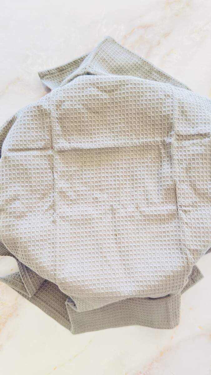 Pita bread dough placed in a bowl and covered with a gray kitchen towel for rising.