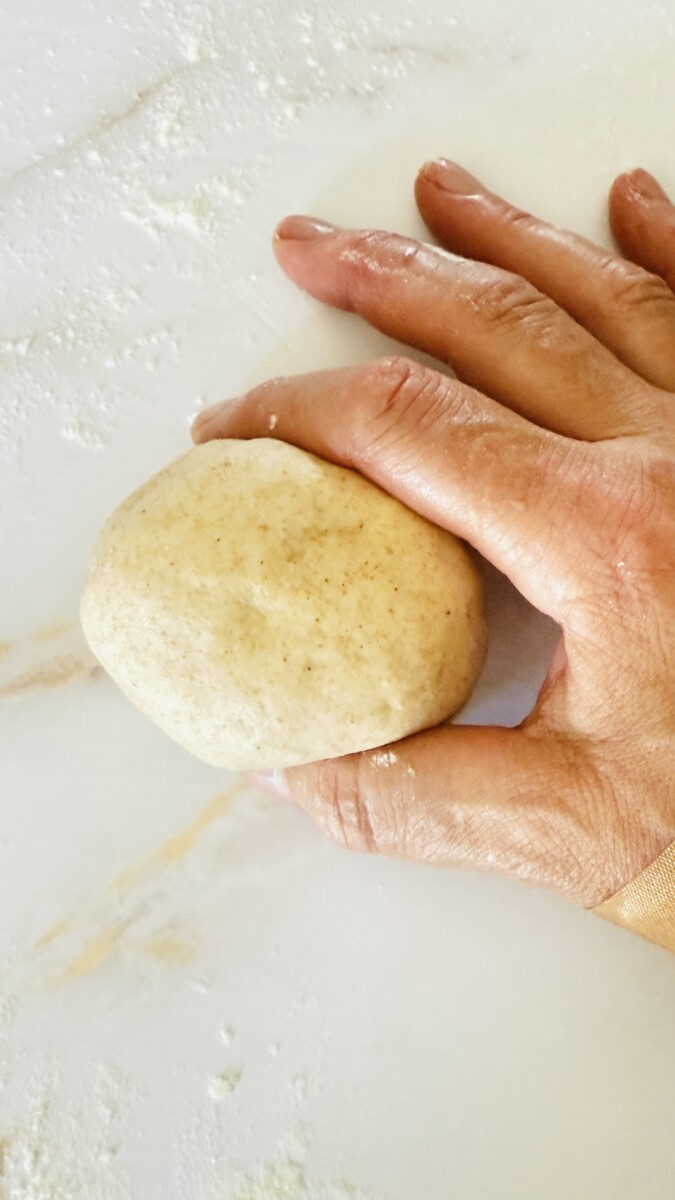 Finished pita bread dough shaped into a smooth round ball, ready for resting.