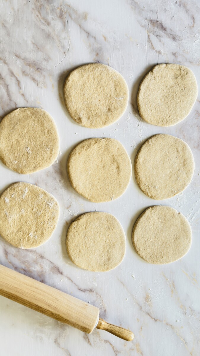 Rolled pita bread circles resting on the counter before cooking.