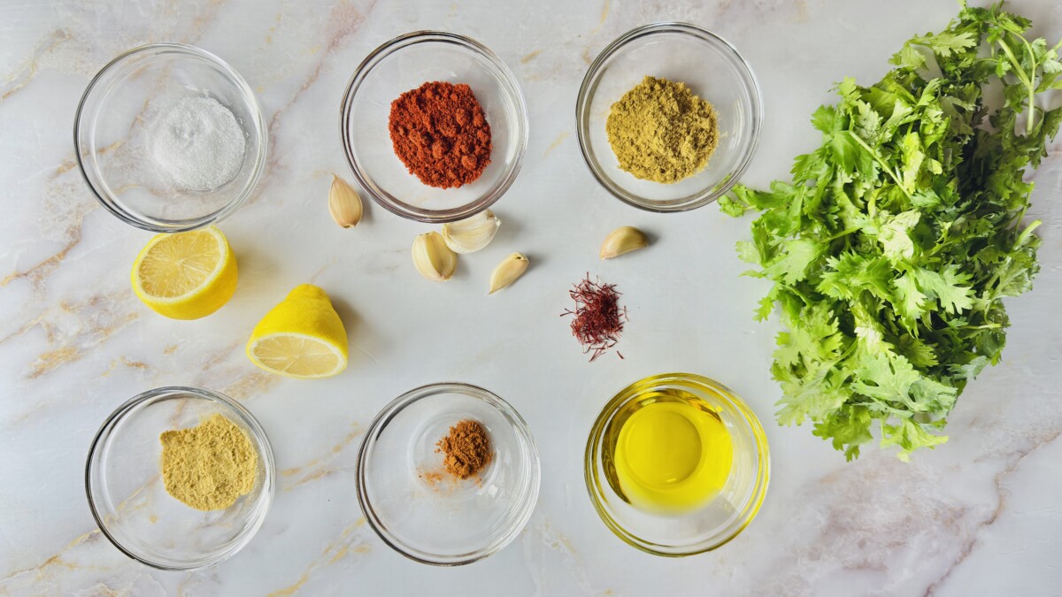 Ingredients for Moroccan chermoula marinade — fresh cilantro, garlic, spices, saffron water, olive oil, lemon zest, and juice ready to blend for the fish tagine.