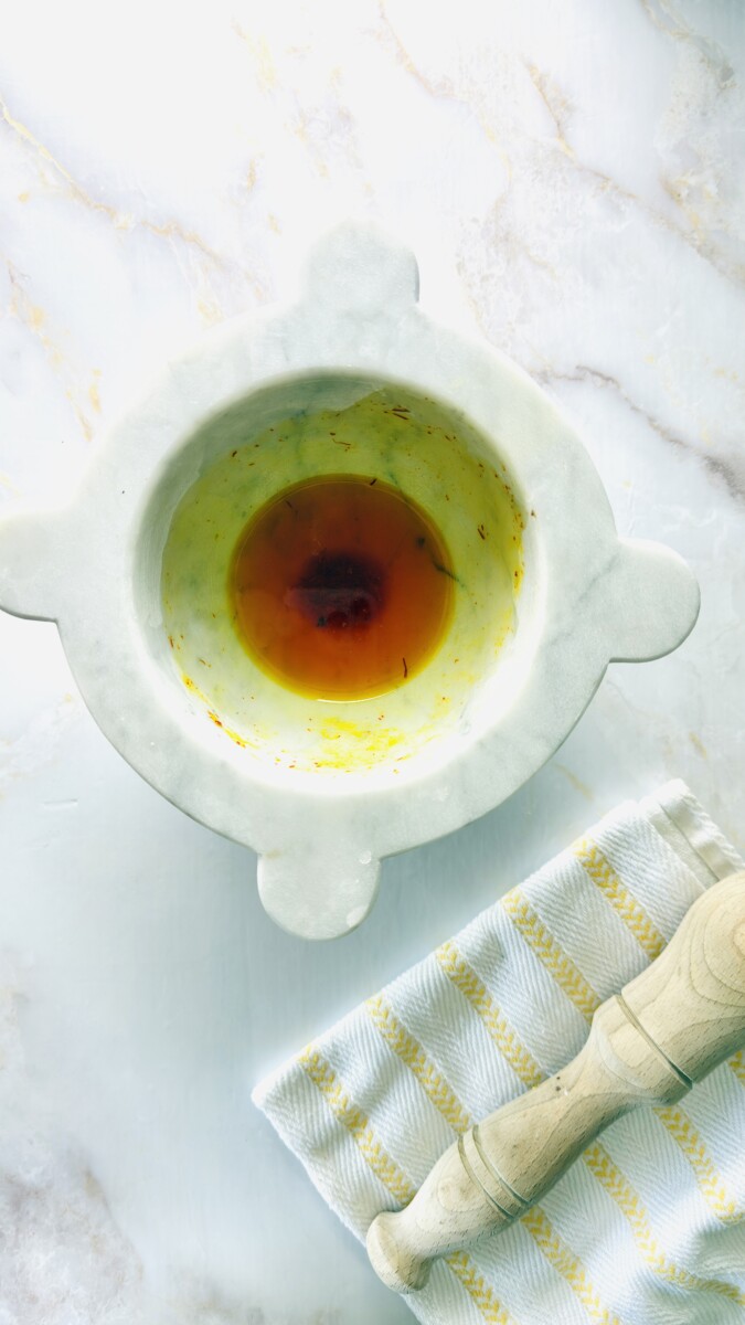 Golden saffron water fully bloomed after melting ice cubes — rich in color and aroma, ready to add to the Moroccan fish tagine chermoula.