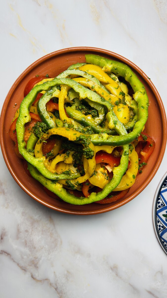 Colorful bell pepper rings layered on top of potatoes in the tagine, adding sweetness and vibrant color to the Moroccan Fish Tagine.