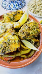 Hero image of Moroccan Fish Tagine with Chermoula and Vegetables served with a side of couscous, tagine lid on the side — a vibrant, authentic Moroccan meal.