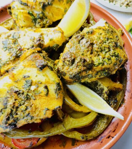 Hero image of Moroccan Fish Tagine with Chermoula and Vegetables served with a side of couscous, tagine lid on the side — a vibrant, authentic Moroccan meal.