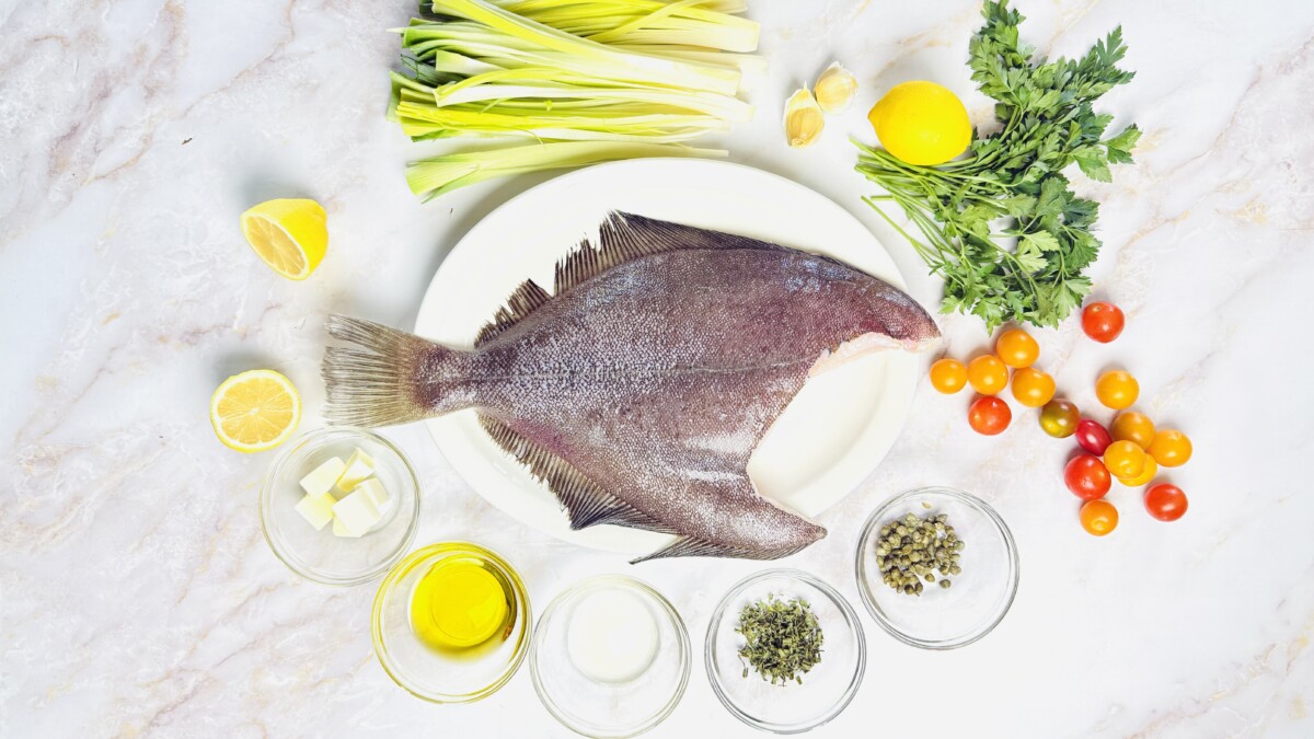 Ingredients laid out for baked whole Petrale sole with cherry tomatoes, capers, lemon, fresh herbs, leeks, garlic, white wine, olive oil, and butter.