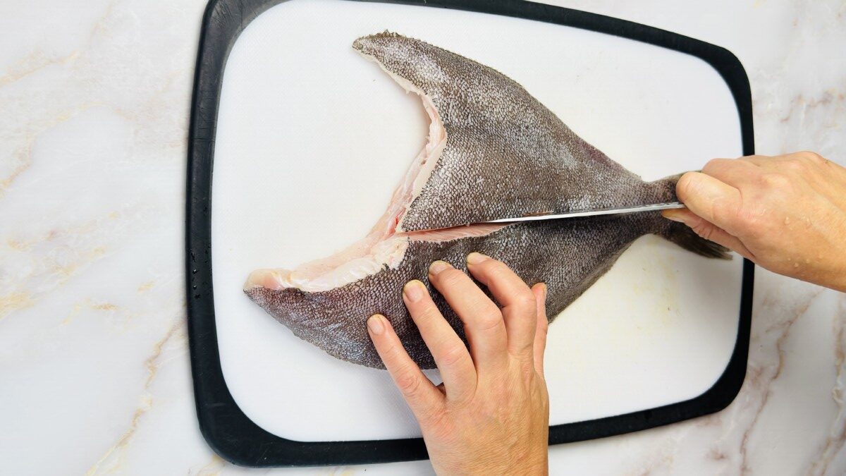 Making a shallow center cut along the back of a whole Petrale sole to prepare it for roasting.