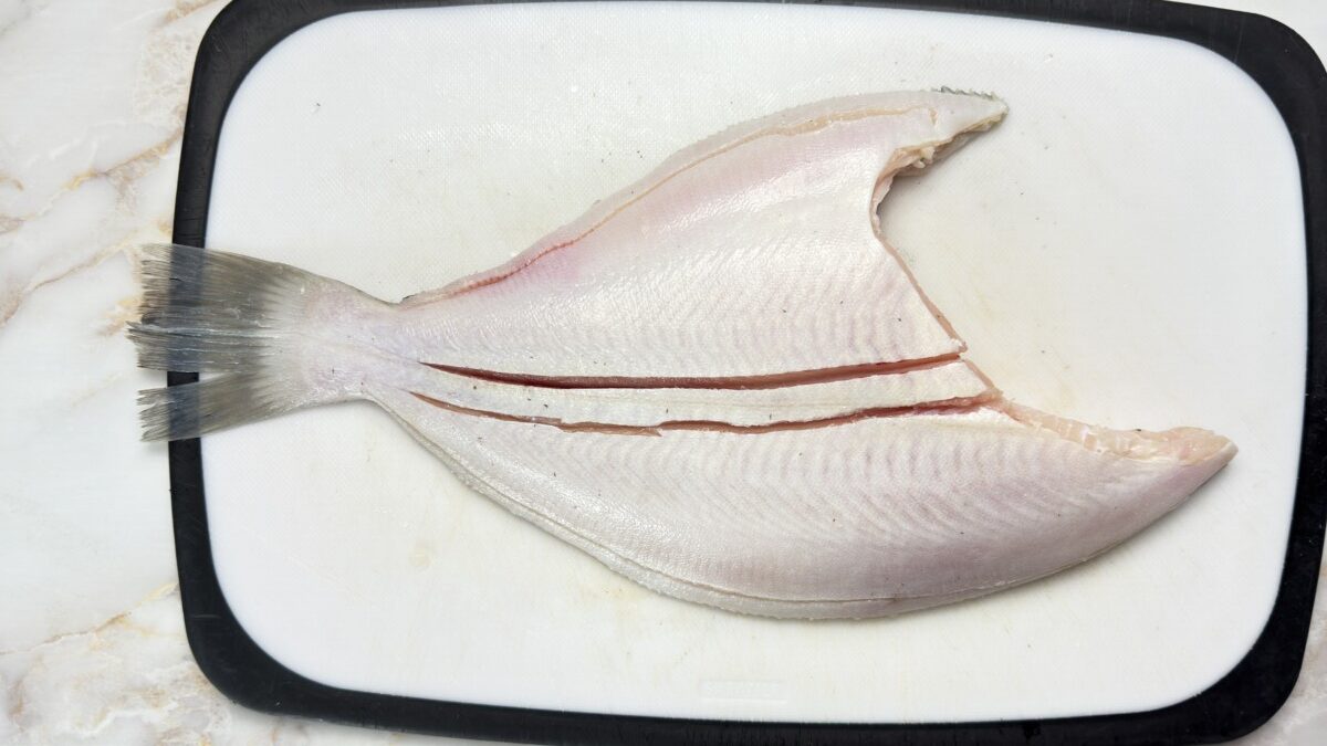 Making similar cuts on the underside of the whole Petrale sole for even baking and easy serving.