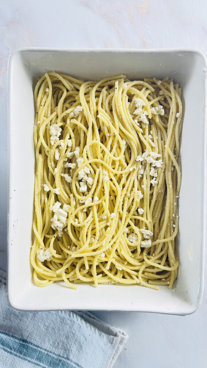 Pasta arranged in even lines across the buttered baking dish, forming the first layer of Greek Pastitsio.