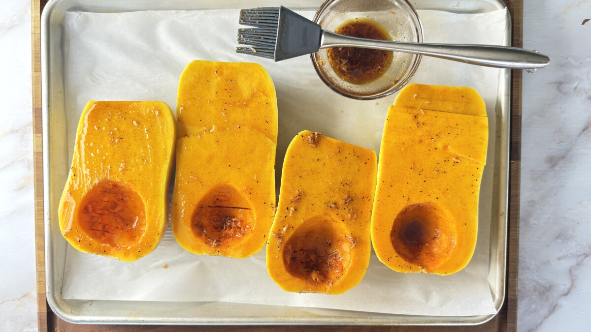Brushing olive oil mixture on bottom of hasselback butternut squash with pastry brush