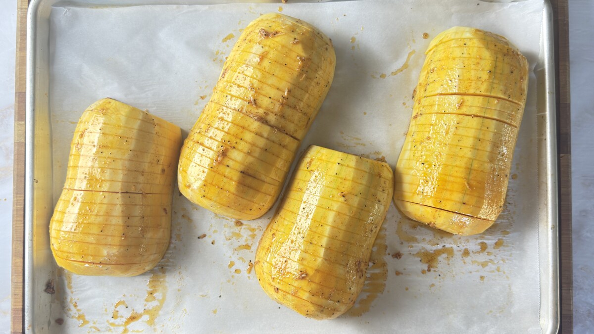 Brushing seasoned oil mixture on top of hasselback butternut squash slices
