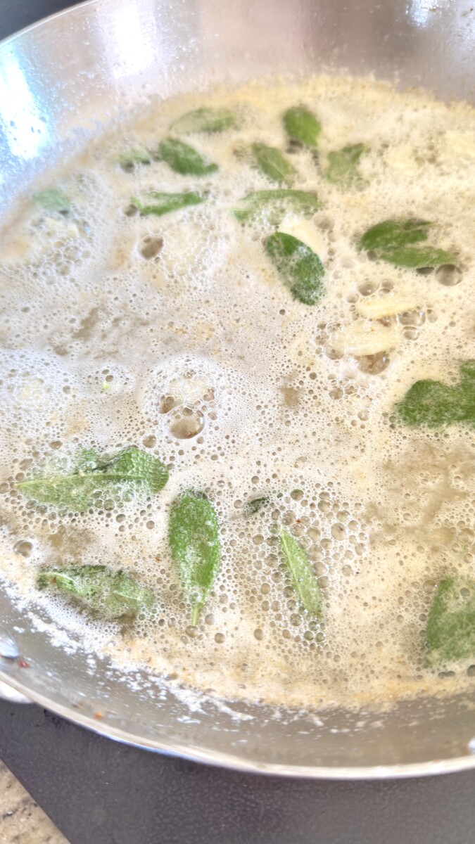 Sage leaves and garlic cooking in melted butter with pancetta drippings in a skillet